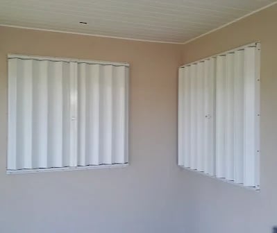 Accordion hurricane shutters fitted to two windows inside a Grand Cayman home